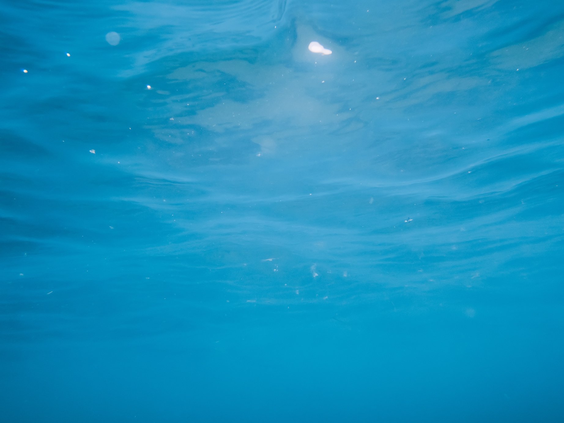 Underwater turquoise texture in ocean. Bubbles in tropical sea.